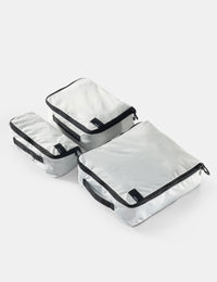 Set of white packing cubes with black zippers on a white background