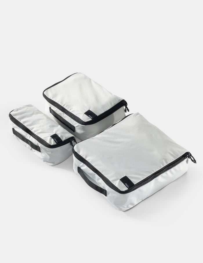 Set of white packing cubes with black zippers on a white background