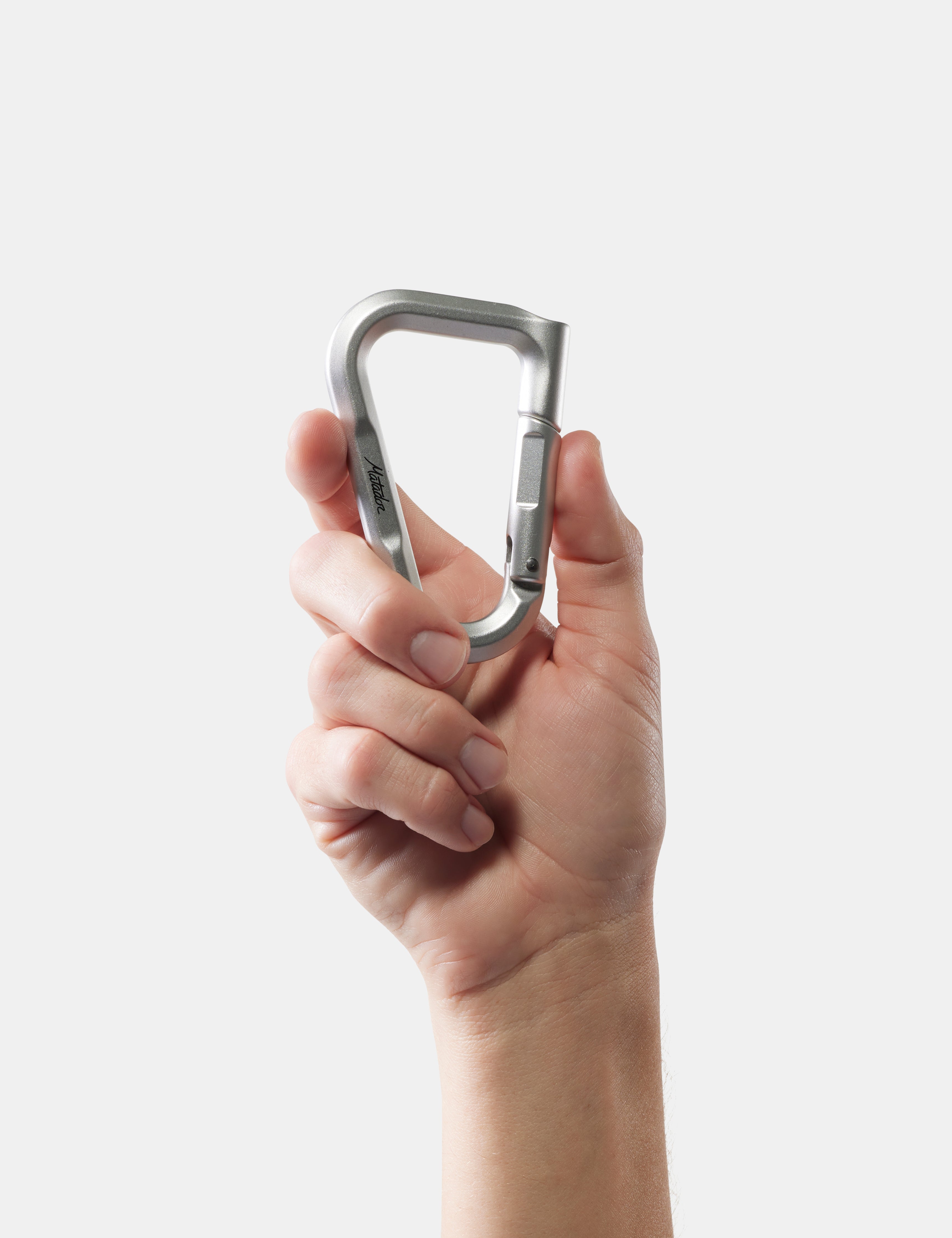 Hand holding a metallic carabiner against a white background