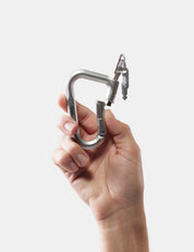 Hand holding a metal carabiner against a white background