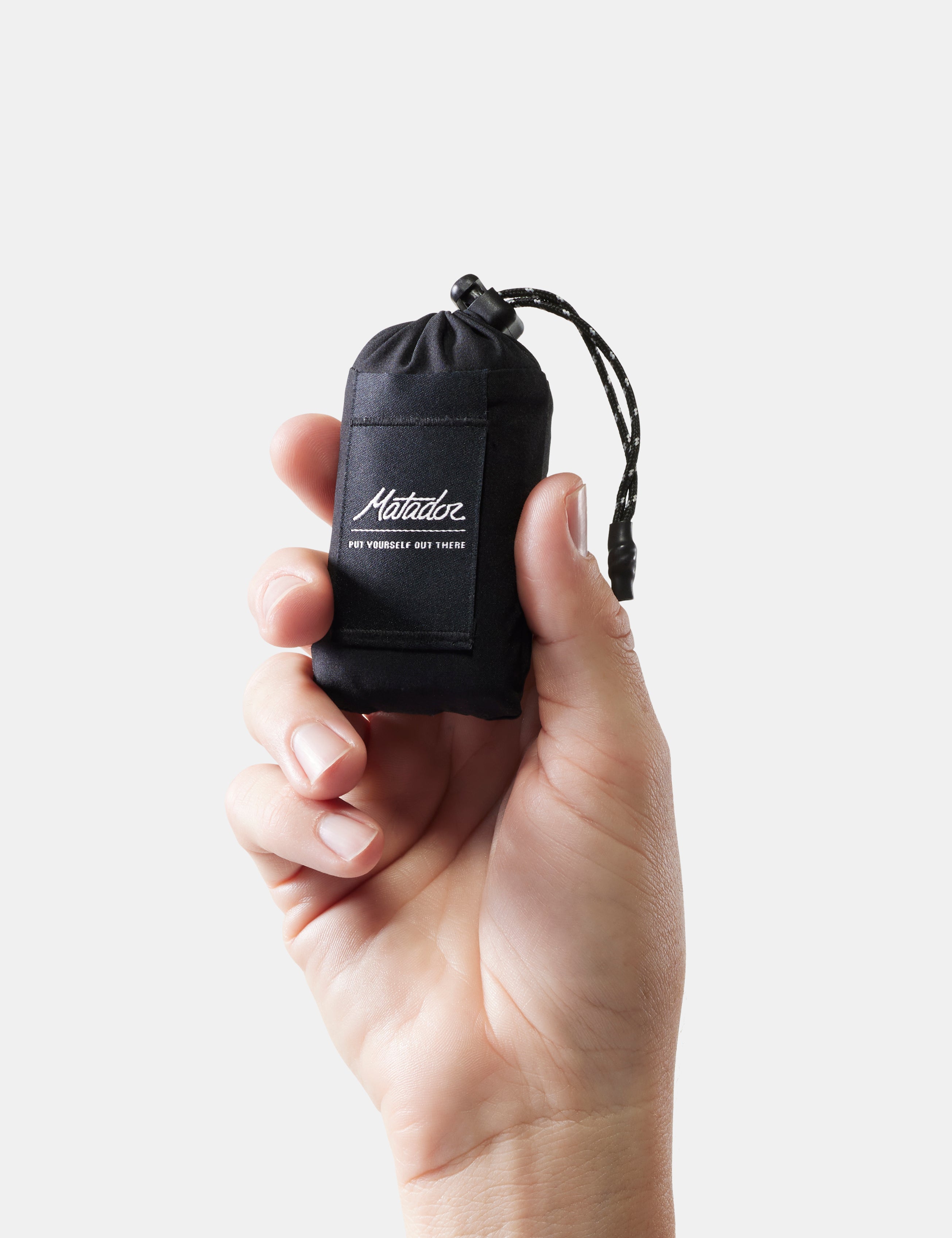 Hand holding a black drawstring pouch with a brand logo on a light gray background