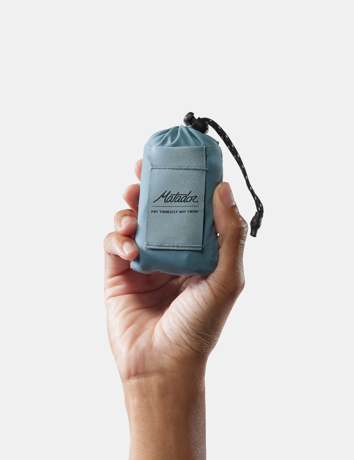 Hand holding a small blue drawstring bag with 'Matalan' branding on a light gray background