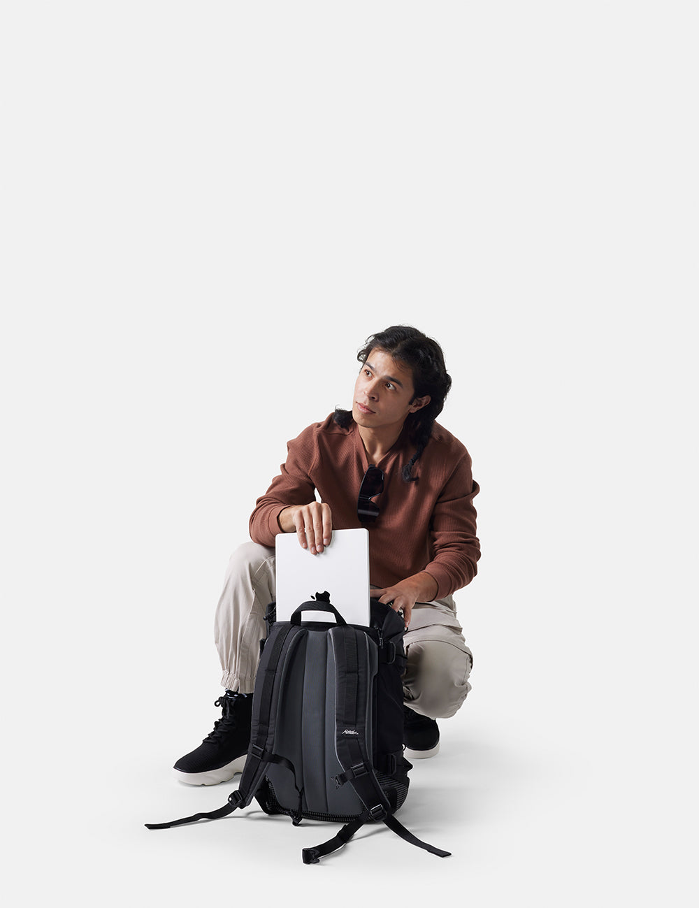 Person sitting with a backpack on a white background