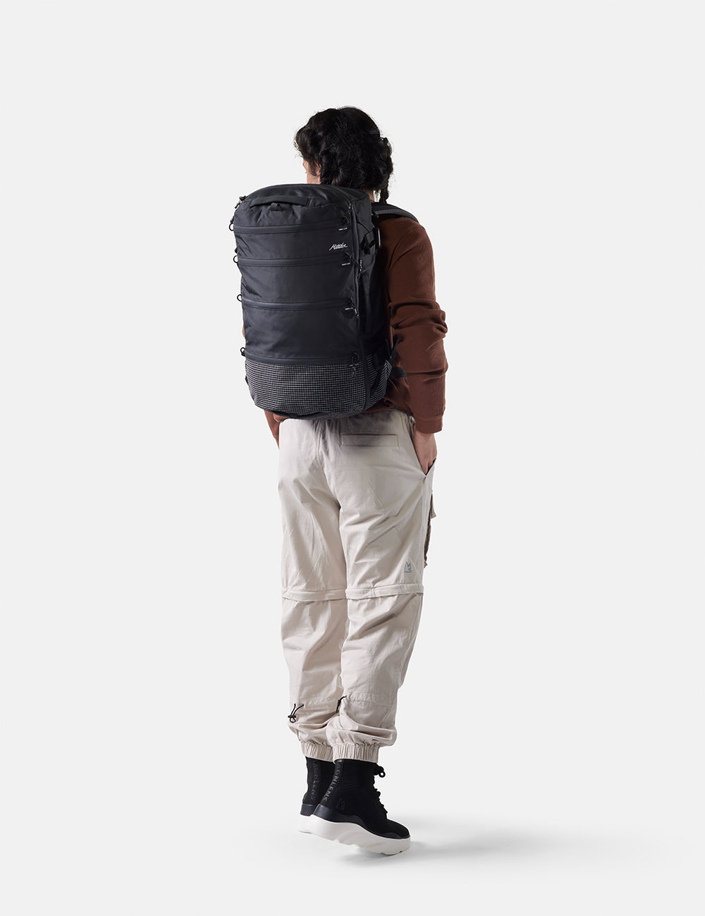 Person wearing a large black backpack on a white background