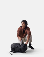 Person opening a black backpack on a white background