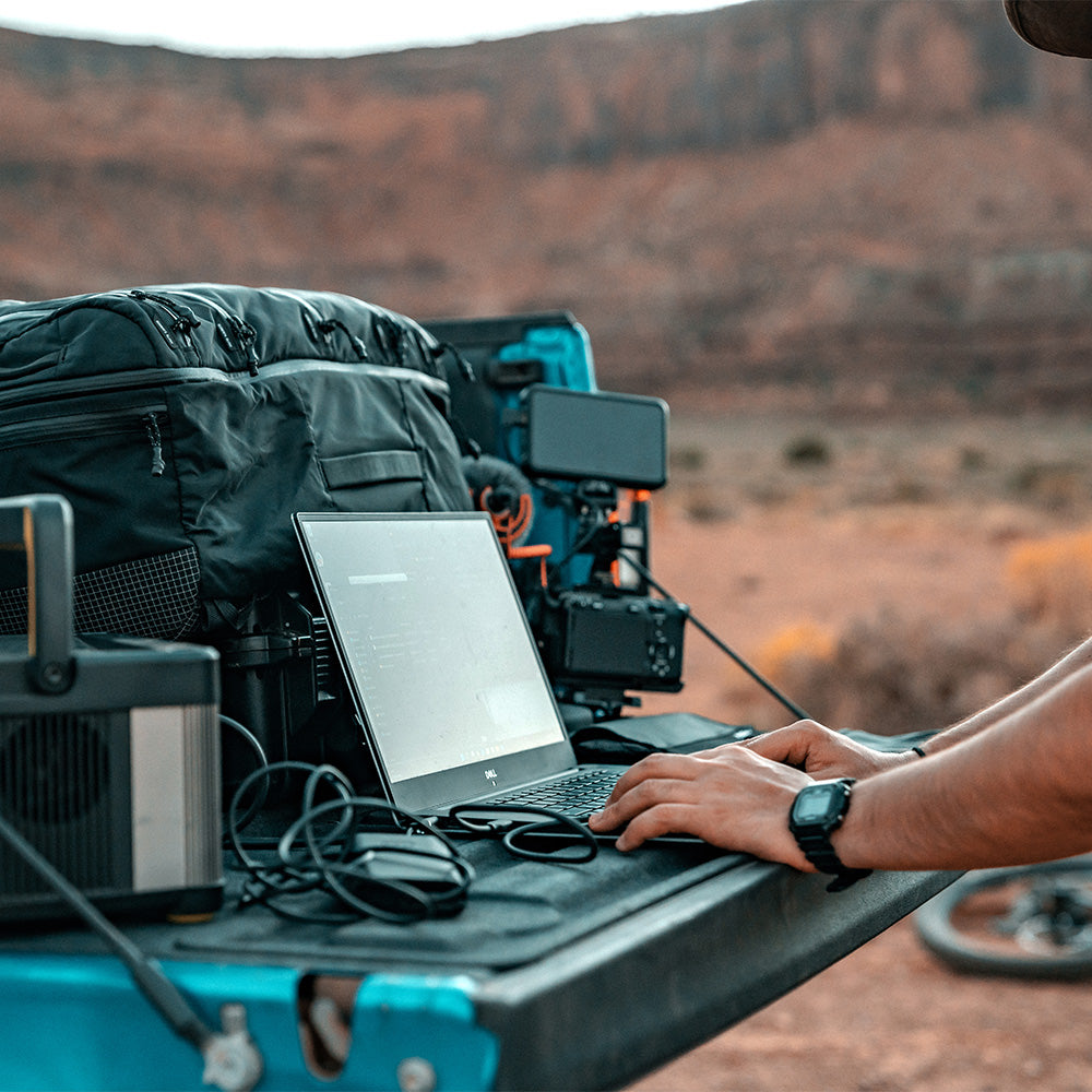 person on laptop in truck bed full of gear
