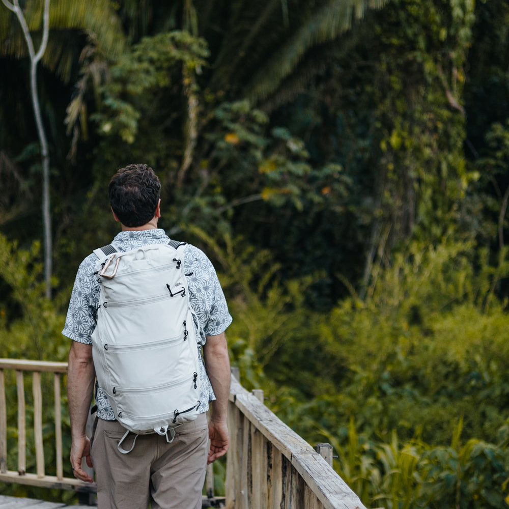 man wearing white seg45, walking along tropical boardwalk