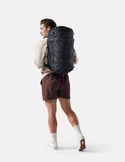 Person wearing a large black backpack on a white background