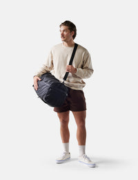 Man holding a duffel bag against a white background