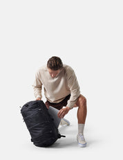 Man unpacking a black backpack on a white background