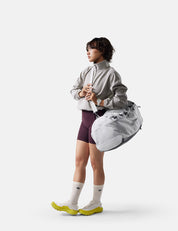 Person wearing a light gray jacket and purple shorts with a white background