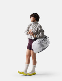 Person wearing a light gray jacket and purple shorts with a white background