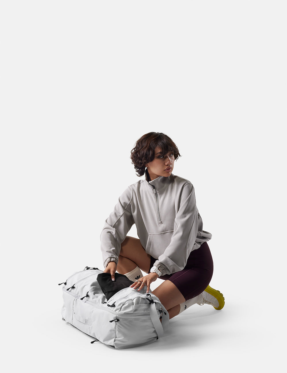 Person sitting on a white backpack against a white background