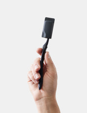 Hand holding a black toothbrush and cap against a white background