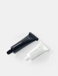 Two tubes , one black and one white, on a light gray background