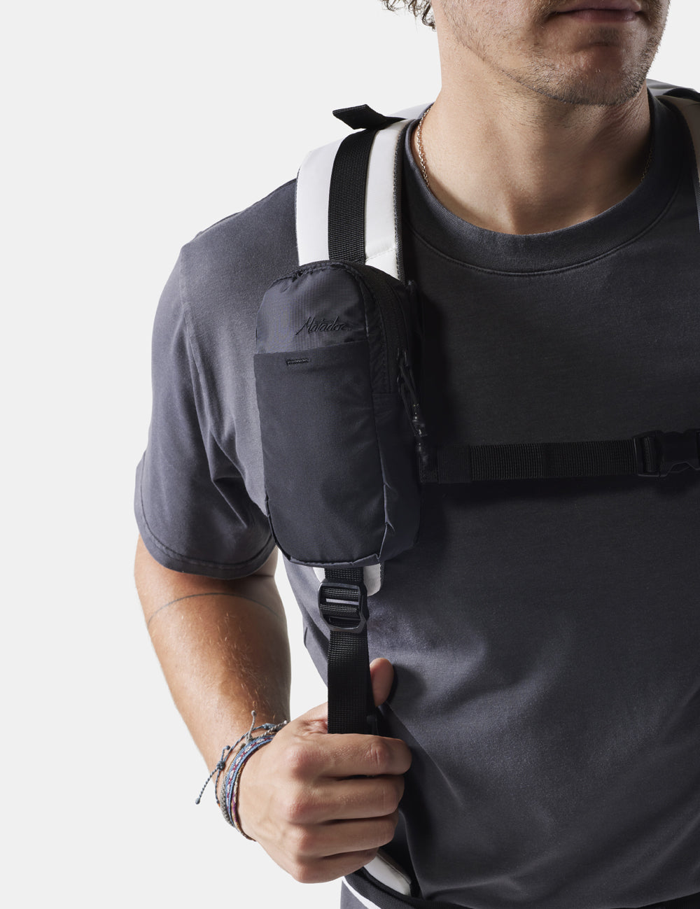 man on white background wearing black speed stash on his backpack