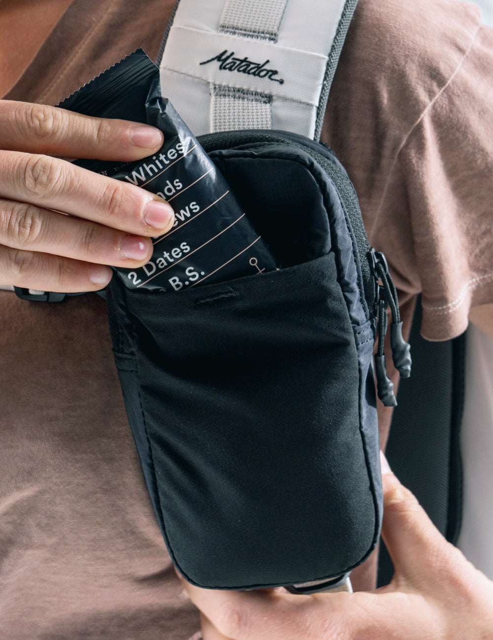 placing a protein bar in front stretch pocket of black speed stash