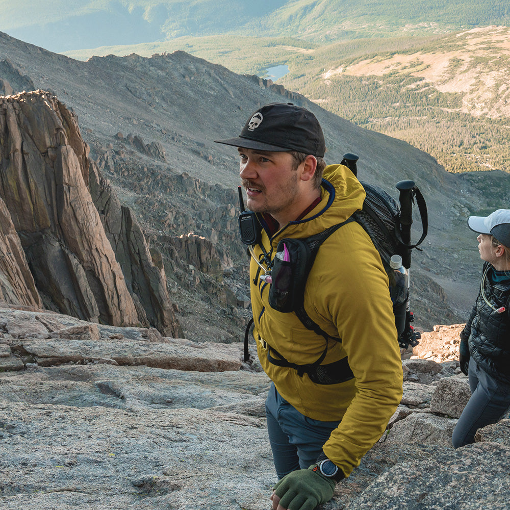 man on rocky mountain side wearing backpack with speed stash