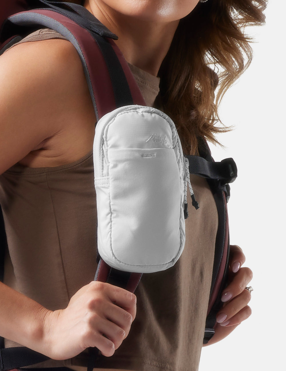 Woman wearing a garnet backpack with straps over her shoulders on a white background