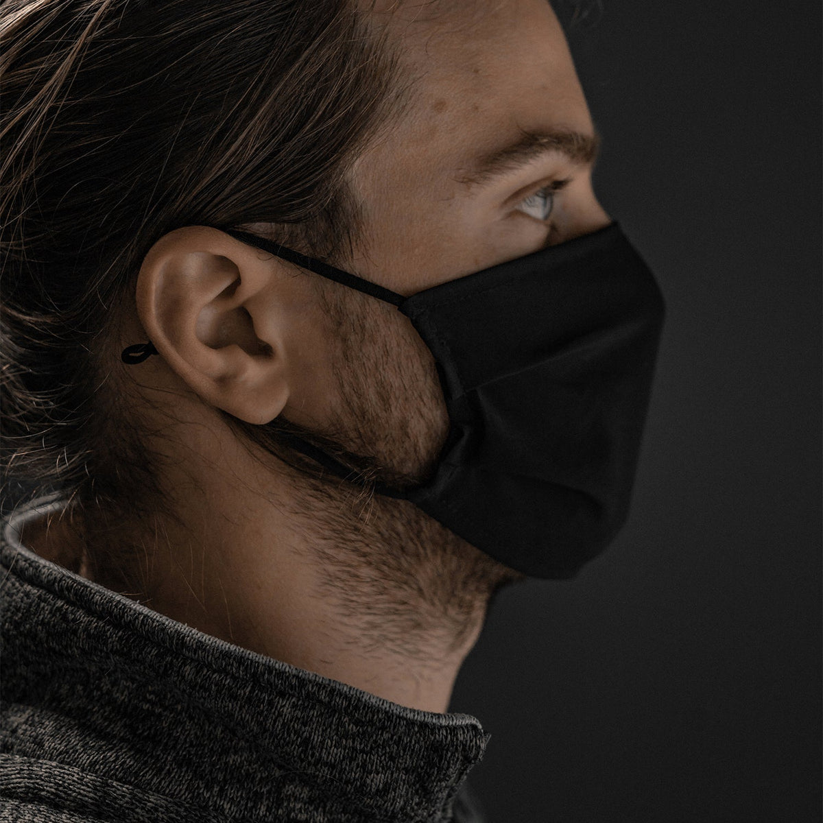 A man with a beard and long hair wearing the black packable keychain mask.