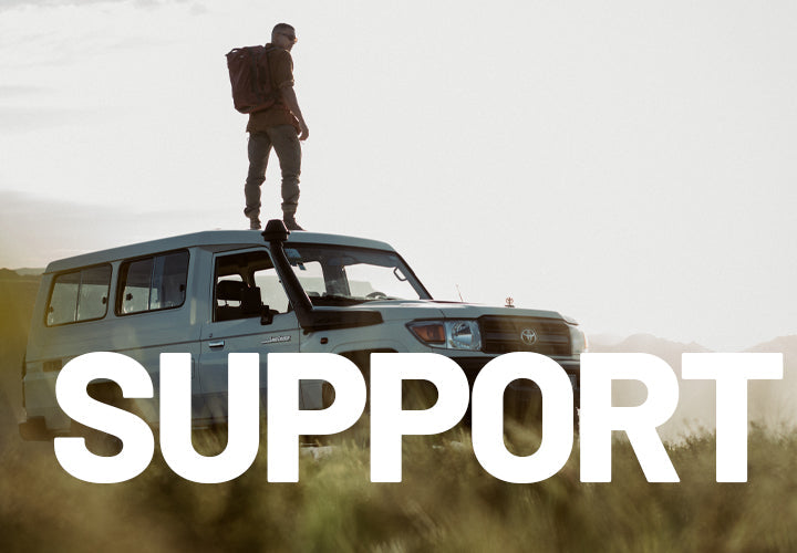 "Support" over image of man standing on vehicle, looking out over landscape