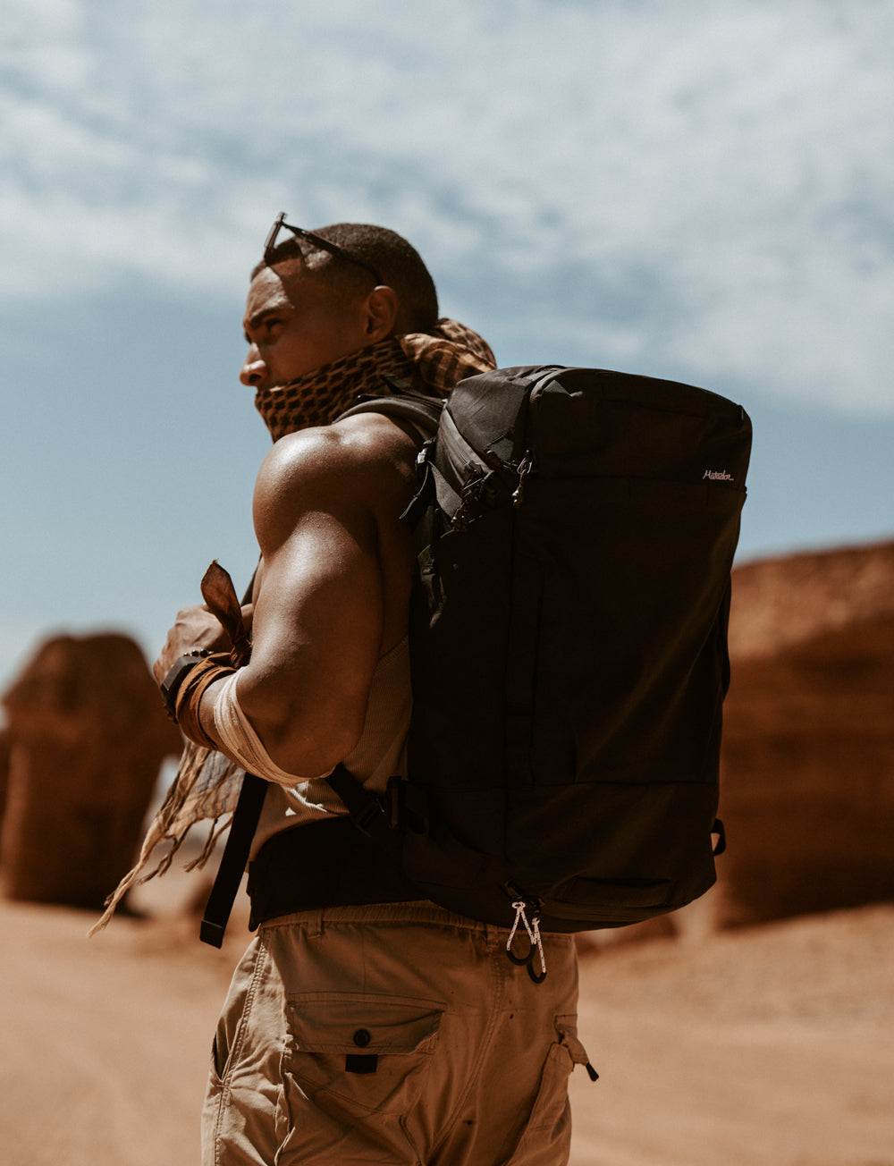 Man in desert setting with scarf around his face, wearing black globerider35 pack