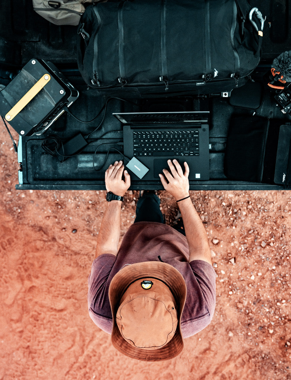 top view of man in desert setting, working on computer off the end of a truck bed