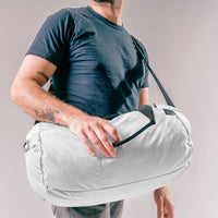 man wearing arctic white duffle over his shoulder and across his body