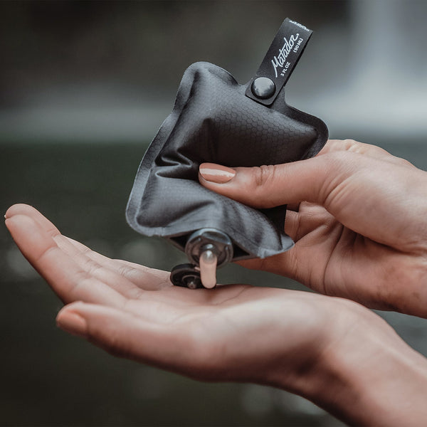 Hands squeezing liquid out of FlatPak Toiletry Bottle into palm