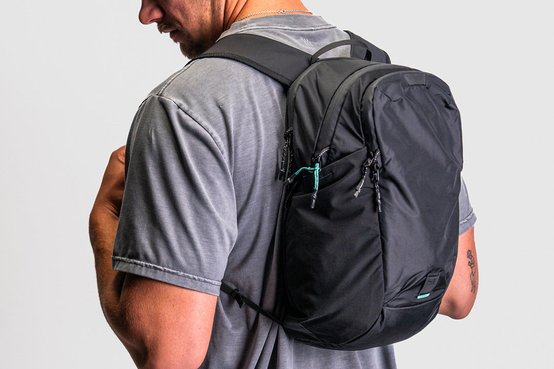 person wearing a black backpack with teal zipper pulls